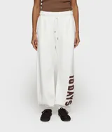 Pantalón deportivo oversize de felpa, color blanco, con cintura elástica ajustable con cordón, bolsillos laterales y parche con el texto "10 DAYS" en color marrón en la pierna.