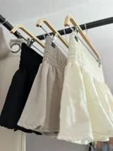 Minifalda de tiro bajo color beige, con cintura elástica fruncida y diseño acampanado con volados.