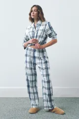 Pijama de dos piezas con estampado de cuadros en tonos azules y blancos. La parte superior es una camisa de manga larga con cuello solapa y cierre frontal de botones. La parte inferior es un pantalón de corte recto con cintura elástica.