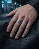 Anillo de acero inoxidable con diseño de eslabones entrelazados tipo cadena, acabado envejecido.