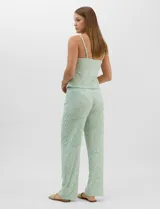 Set de pijama de tres piezas en color verde menta con estampado floral sutil, compuesto por una camisa de manga corta con botones, una musculosa básica y un pantalón largo de corte recto con cordón ajustable en la cintura.