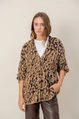 Cárdigan de punto con textura suave y estampado animal print en tonos marrones y beige. Presenta escote en V, cierre frontal con botones y mangas largas holgadas.