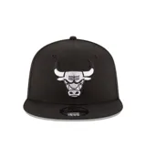Gorra New Era modelo 9Fifty, color negro con el logotipo bordado de los Chicago Bulls en la parte frontal en color blanco. Cuenta con visera plana y cierre ajustable en la parte trasera.