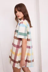 Vestido corto de algodón color negro, con mangas cortas, cuello redondo y diseño con tablas frontales y traseras que le otorgan una caída holgada.