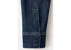 Camisa azul oscuro de denim con cuello alto y detalle de bufanda integrada en el mismo tejido.
