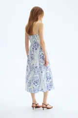 Vestido midi de tejido liviano color blanco con estampado floral en tonos azules, escote cuadrado, breteles finos y falda con vuelo.