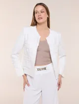 Chaqueta corta confeccionada en tejido bouclé texturizado de color blanco con sutiles lentejuelas. Presenta escote redondo, diseño abierto al frente, bolsillos frontales con solapa y mangas largas con puños de tela lisa.