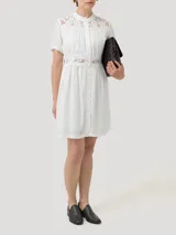 Vestido midi de lino orgánico y viscosa en color blanco, con cuello mao, mangas cortas y cierre frontal con botones. Presenta detalles de encaje en los hombros, el pecho y la cintura, además de forro interior a tono.
