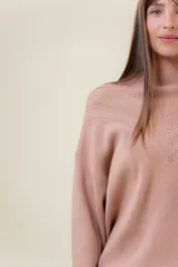 Sweater tejido de punto color blanco, con cuello alto y diseño en relieve tipo chevron en la parte frontal. Presenta un calce holgado con terminaciones acanaladas en puños y ruedo.