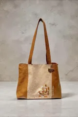 Cartera tipo shopper de cuero, con diseño combinado en colores caramelo y perla, asas de hombro y arte pintado a mano en el frente.