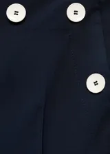 Pantalon de vestir negro de corte recto y tiro medio. Presenta detalle de botones decorativos en contraste en la cintura, bolsillos laterales y bolsillos de ribete en la parte posterior.