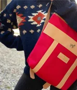 Mochila color borgoña con detalles en cuero marrón. Tiene correas ajustables, cierre superior y logo de la marca en el frente.