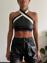 Top halter de cuero sintético negro con tiras cruzadas al cuello en color blanco.