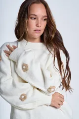 Sweater color crema de hilado frizado con cuello redondo y apliques de flores color beige en las mangas.