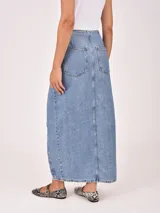 Falda larga de denim color gris oscuro, con diseño cruzado frontal (wrap) que se ajusta con botones plateados, creando una abertura pronunciada.