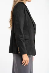 Blazer negro de textura gamuzada con solapas clásicas, cierre frontal de dos botones y bolsillos laterales con solapa.