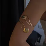 Brazalete dorado para el brazo con cadena y dos dijes de conchas marinas.