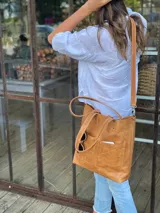 Bolso tipo tote bag color suela, de cuero, con doble asa de mano y correa larga extraíble y ajustable. Tiene dos bolsillos externos grandes.