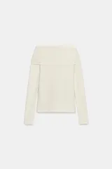 Top de punto color crema con escote recto estilo hombros descubiertos, manga larga y detalle de hebilla metálica en el hombro.