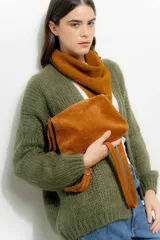 Bandolera pequeña de gamuza color tostado, con correa larga ajustable y cierre superior. Presenta un diseño minimalista y compacto.