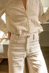Pantalón de corte wide leg y tiro medio, confeccionado en lino. Presenta diseño de pierna ancha, cierre frontal con botón y bolsillos laterales.