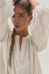 Blusa blanca de algodón con hilos metalizados, cuello mao y escote en V.