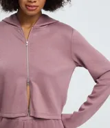 Campera corta con capucha fija, cierre frontal con cremallera y mangas largas, confeccionada en tejido modal con acabado satinado.