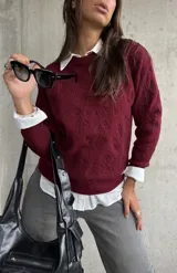 Sweater de punto color bordó con diseño de bordado floral en relieve, cuello redondo y mangas largas con puños acanalados.