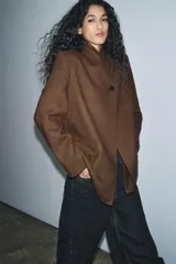 Blazer marrón de la colección Zara Woman, confeccionada en hilatura con 38% lana. Presenta cuello subido, manga larga con abertura y botones, bolsillos con solapa en el delantero y forro interior. Cierre frontal con un botón.