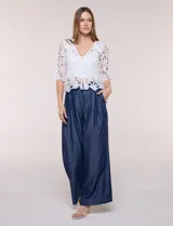 Bolero corto de encaje blanco con motivo floral y transparencias, escote en V pronunciado y mangas tres cuartos.