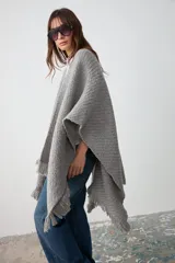Ruana de tejido artesanal en lana merino, lino y viscosa, con textura aireada y terminación de flecos en los bordes. Diseño versátil y envolvente, ideal para usar como abrigo ligero.
