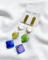 Aros colgantes con piezas rectangulares doradas y piedras irregulares de colores blanco nacarado, verde y azul, unidas por argollas doradas.