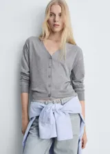 Cardigan de punto fino en color gris, con cuello en pico y cierre frontal de botones. Presenta un diseño recto de manga larga.