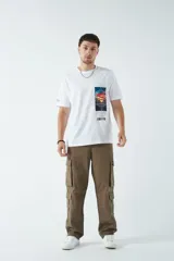 Pantalón cargo de canvas color marrón, con tiro medio, múltiples bolsillos laterales y traseros, y cierre frontal con botón y cremallera.