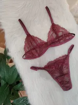 Conjunto de lencería de encaje bordó, compuesto por un corpiño triangular con breteles regulables y una bombacha tipo tanga con laterales ajustables.
