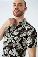 Camisa de manga corta con estampado botánico de hojas en tonos azul y blanco. Presenta cuello clásico, cierre frontal abotonado y corte slim.