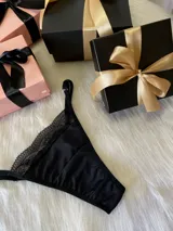 Pack de tres bombachas tipo tanga con diseño de encaje y tiras ajustables. El set incluye modelos en colores bordó, negro y blanco, confeccionados con detalles de encaje floral y terminaciones delicadas.