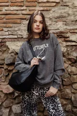 Buzo gris de felpa oversize con estampado frontal de mariposa y texto.