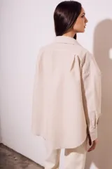 Camisa oversize color arena con rayas verticales marrones, de manga larga y cuello clásico.