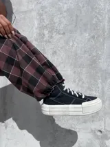 Pantalón de corte holgado tipo barrel con diseño de cuadros en tonos bordó, negro y blanco. Confeccionado en tela viyela, cuenta con cintura elástica y puños ajustados en los tobillos.