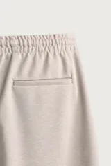 Pantalón jogger color beige de tejido transpirable y elástico con cintura elástica ajustable con cordón, bolsillos frontales y bajo con vuelta.
