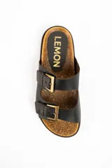 Sandalias de cuero negro con diseño de doble tira con hebillas metálicas doradas, plantilla de corcho y suela plana marrón.