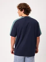 Remera negra de manga corta con diseño deportivo, parte superior de las mangas en color gris con ribete blanco y estampa frontal con la marca Rusty.