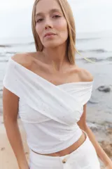 Top off-the-shoulder confeccionado en microtul con apliques brillantes. Presenta un diseño cruzado en el frente y ajuste al cuerpo.