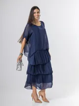 Vestido largo azul marino de seda italiana, con diseño de volados escalonados en la falda y una sobrecapa superior con mangas cortas amplias.