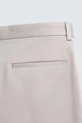 Pantalón chino de corte regular fit, confeccionado en tejido de algodón con elasticidad. Presenta bolsillos frontales, bolsillos traseros de vivo y cierre frontal con cremallera y botón.