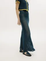 Conjunto de tejido calado color azul petróleo con detalles en amarillo. Incluye un cárdigan corto con botones y una falda larga recta con pretina elástica.