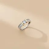 Anillo de plata 925 con baño de oro, presenta un diseño con una piedra central de circonia redonda flanqueada por dos barras doradas y engaste de circonias baguette en los laterales.