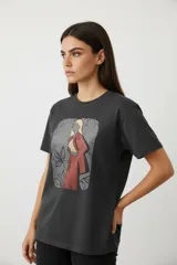 Remera de algodón manga corta con cuello redondo y corte al cuerpo. Presenta un estampado central con diseño artístico y detalles de studs aplicados.
