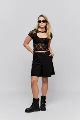 Top de encaje blanco con diseño ajustado al cuerpo, mangas cortas y detalle de cut-out en el escote.